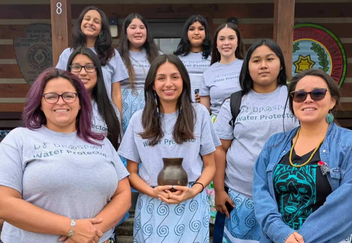 Junior NAIWA Daughters stand with the Longperson before the Eastern Band of Cherokee Council. Back row (Janée Smith, Zailiana Blythe, Laila Crowe-Taylor, Misha Slee) Second Row (Kyndra Postoak, Marijane Tafoya) Front Row (Kimberly Smith-Mentor, Jasmine Smith, Malia Crowe-Mentor)
